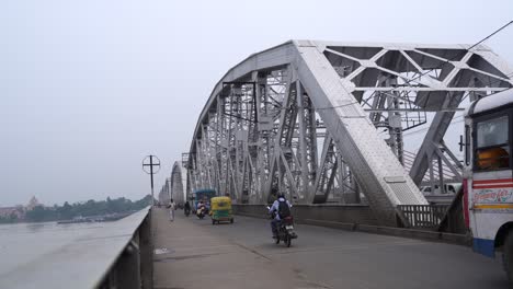 traffic on a metal bridge over a river in india
