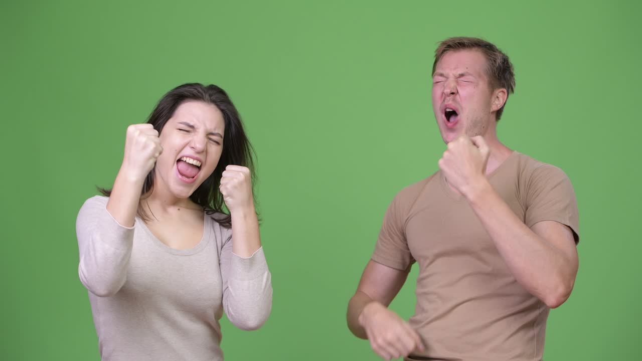 Young couple looking excited together against green background
