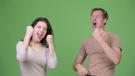 young couple looking excited together against green background