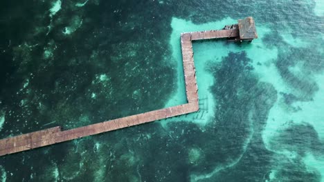paseo marítimo de madera sin barandilla en el océano tropical con coral arenoso debajo de aguas tropicales claras