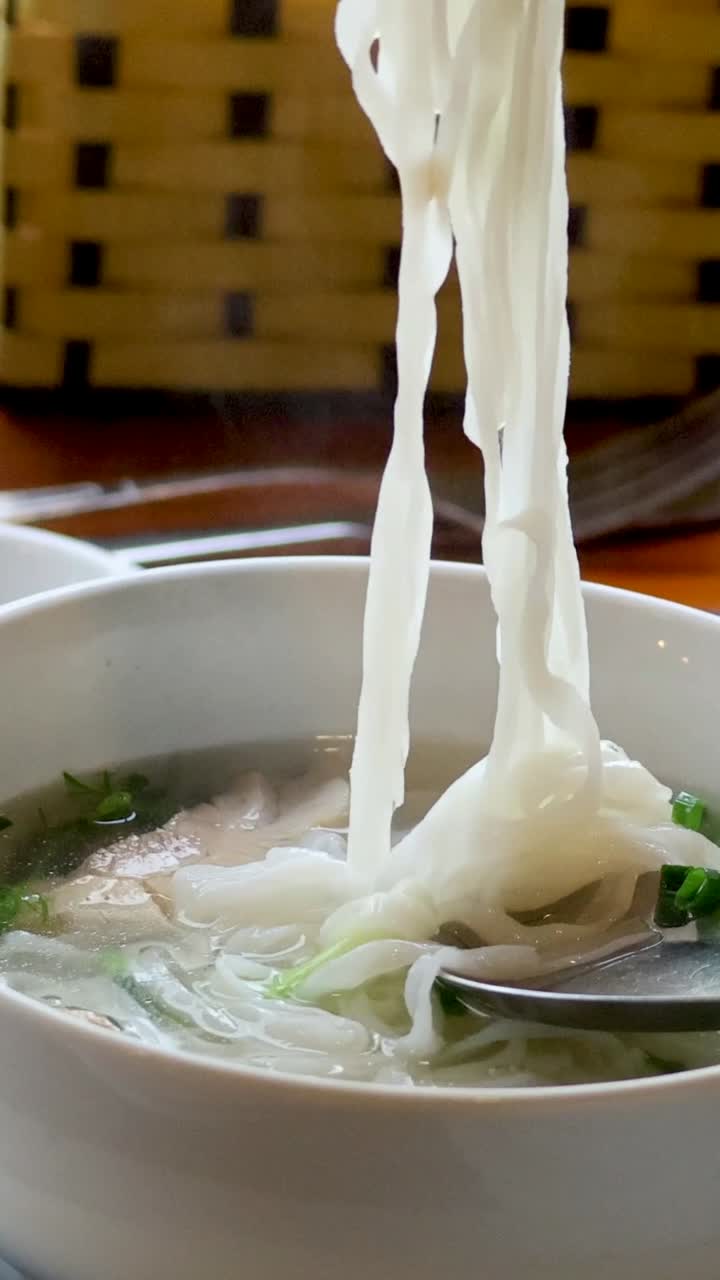 человек ест суп из лапши за обеденным столом