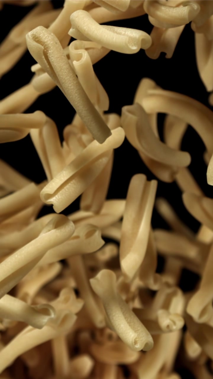 Pasta secca che cade al rallentatore su sfondo nero