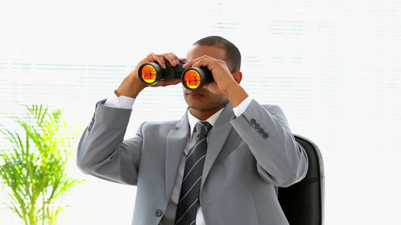 Curious businessman looking through binoculars 