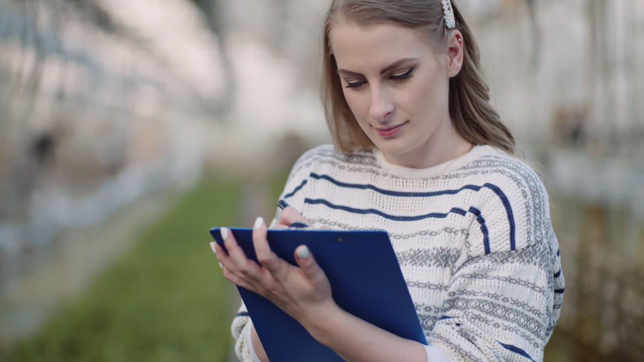 jardinero femenino que examina las plantas en el invernadero