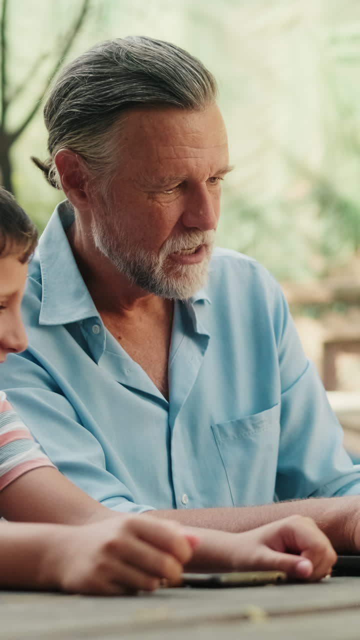 Nonno e nipote sorridenti che digitano al portatile all'aperto