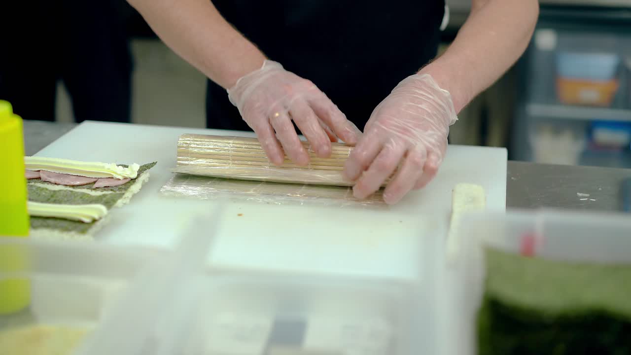 요리사는 매트를 사용하여 일본 롤을 준비합니다.