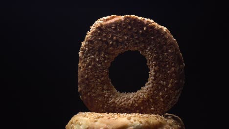 bagels frescos con semillas de sésamo en rotación. fondo negro. primer plano extremo.