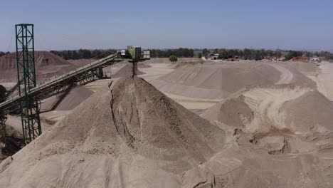 Un-Gran-Camión-Cargado-Con-Arena-Se-Dirige-Hacia-El-Sitio-De-Construcción,-Tomas-Aéreas-Del-Camión-Junto-Al-Sitio-De-Construcción-Y-Los-Materiales