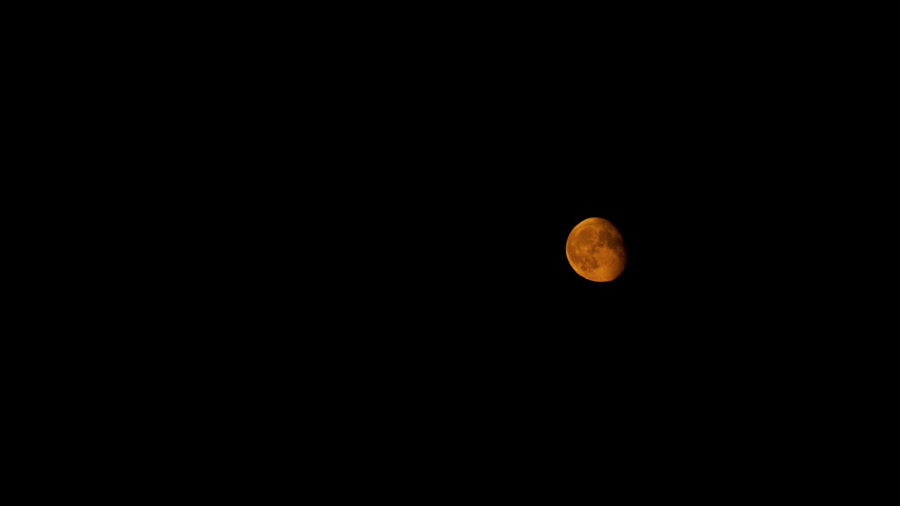 Majestic red moon in night sky with flowing clouds, time lapse