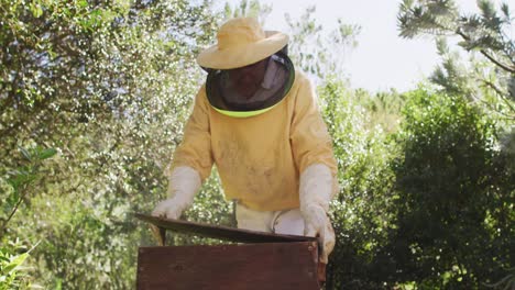 Kaukasischer-Männlicher-Imker-In-Schutzkleidung,-Der-Bienenstock-öffnet