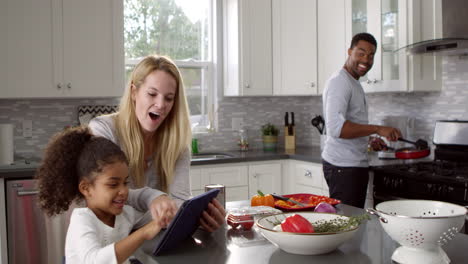 Mamá-E-Hija-Usan-Una-Tableta-Mientras-Papá-Prepara-La-Comida,-Filmada-En-R3d