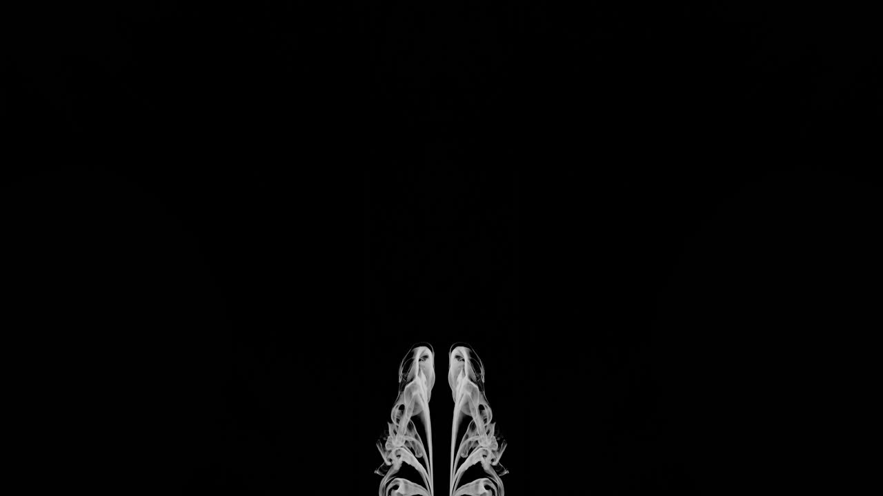 フレームの下部中央から上方および外側に向かって移動する、鏡に映したうっすらとした煙の流れのワイドショット。移動するにつれて奇妙な形やパターンを作り出します。