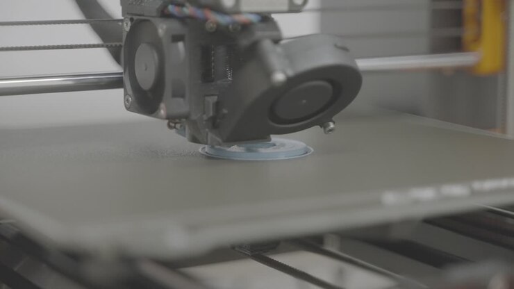 Plano próximo, impressora 3D imprime a base para engrenagem azul em laboratório de sala branca