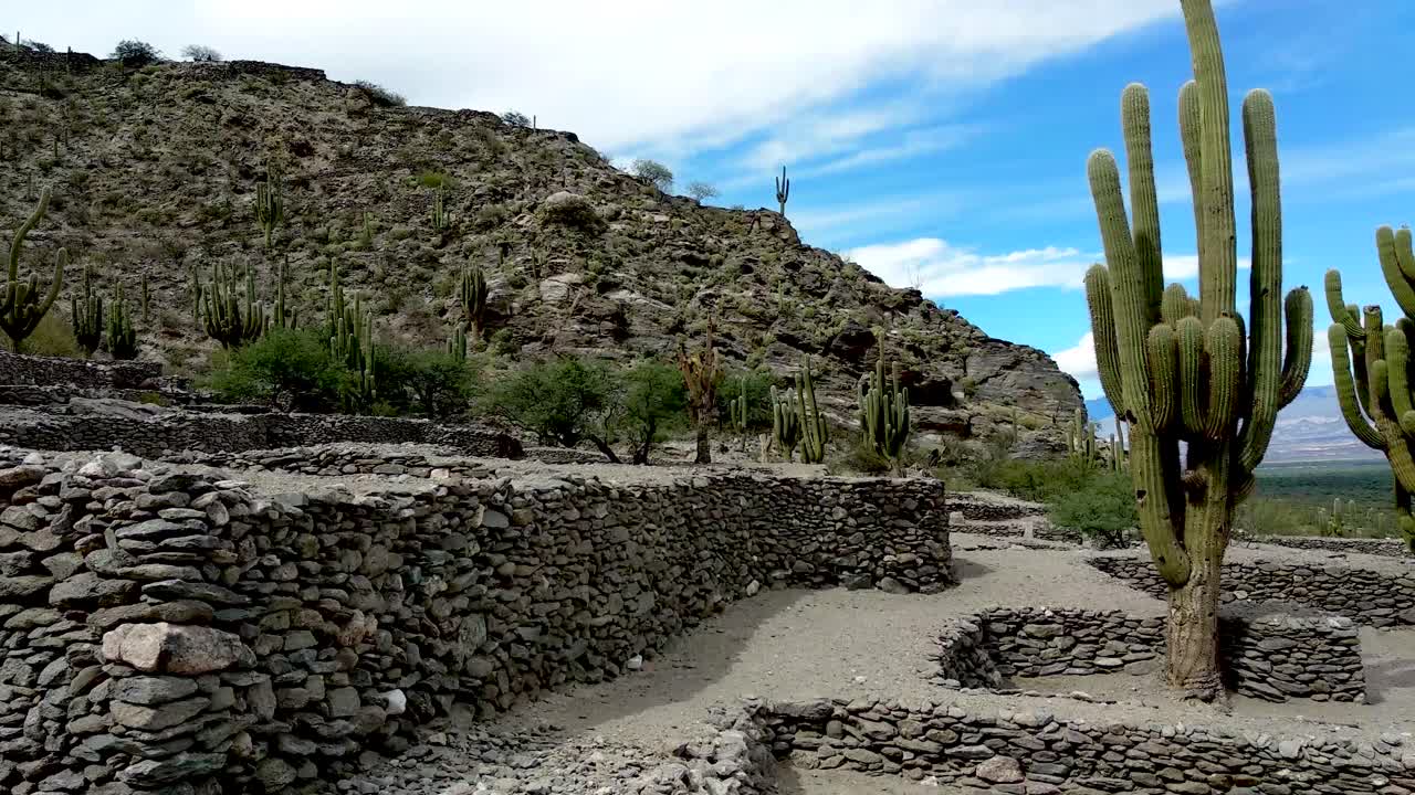 una mujer toma una fotografía de las ruinas y el paisaje en la antigua ciudad de quilmes, un sitio arqueológico en los valles calchaquíes, argentina