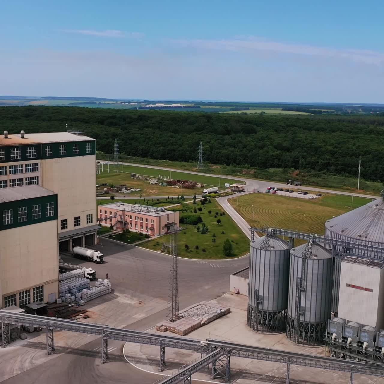 Grain terminals, cargo trains and lorries carrying crop on a modern plant. Grain storage tanks view from above