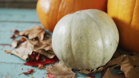 Composition-of-halloween-orange-pumpkins-and-leaves-against-rustic-wooden-surface