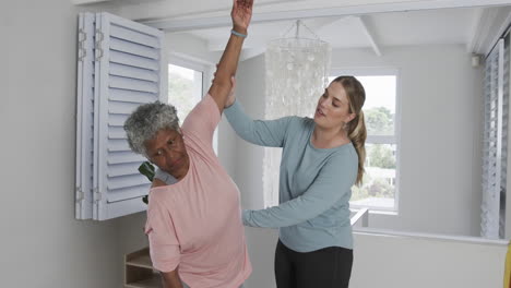 Caucasian-female-physiotherapist-with-senior-woman-exercising,-copy-space,-slow-motion