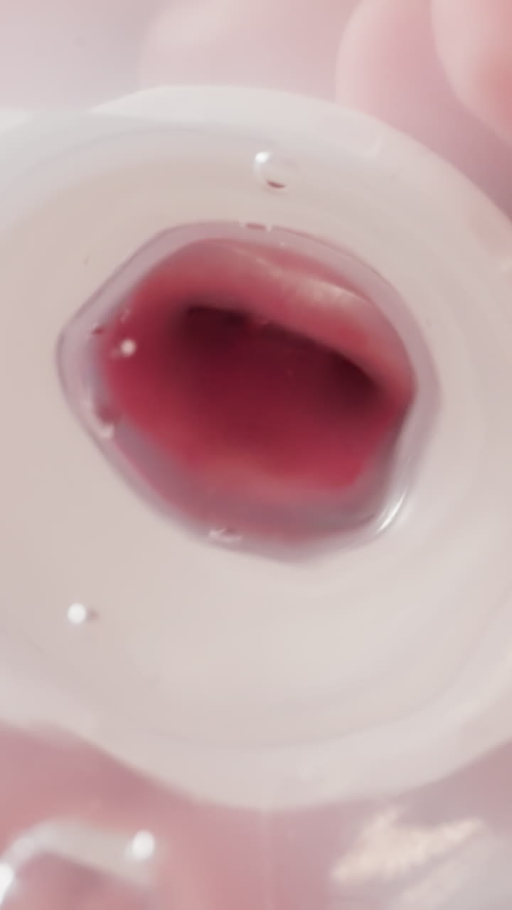 Kid drinks clear water from transparent bottle with nipple. Preschooler boy holds plastic container quenching thirst in kitchen close low angle shot