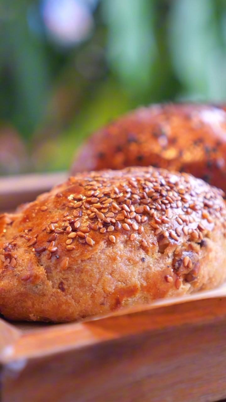 Close-up of Freshly Baked Pastries with Sesame Seeds on a Wooden Tray