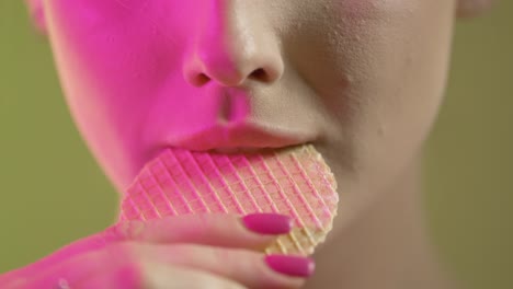 cerca de la cara y la boca de la mujer, tomando un bocado y comiendo una oblea, colorida toma de estudio