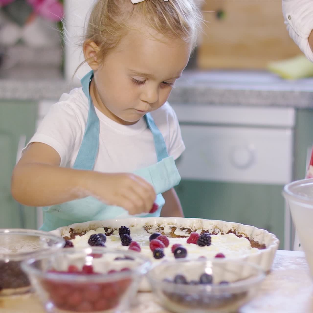 joven madre viendo a su pequeña hija hornear