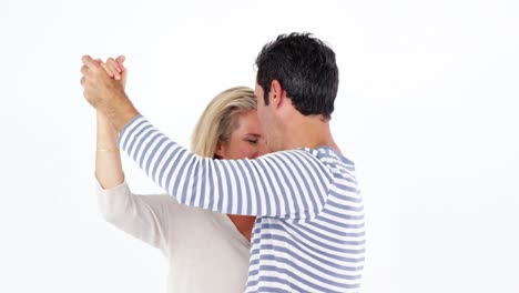 una pareja madura bailando contra un fondo blanco.