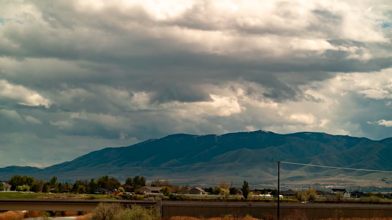 Flowing cloudscape above a valley suburb surrounded by mountains - panoramic time lapse