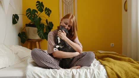 mujer sonriente abrazando gato esponjoso en el dormitorio