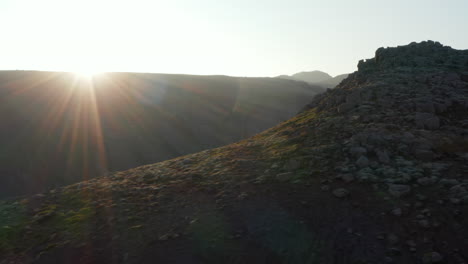 Drohnenansicht,-Die-Um-Den-Felsigen-Hügel-Im-Isländischen-Hochland-Kreist.-Luftbild-Hintergrundbeleuchtung,-Die-Eine-Spektakuläre-Landschaft-Mit-Dampfenden-Fumarolen-Und-Moosbedeckten-Klippen-Offenbart