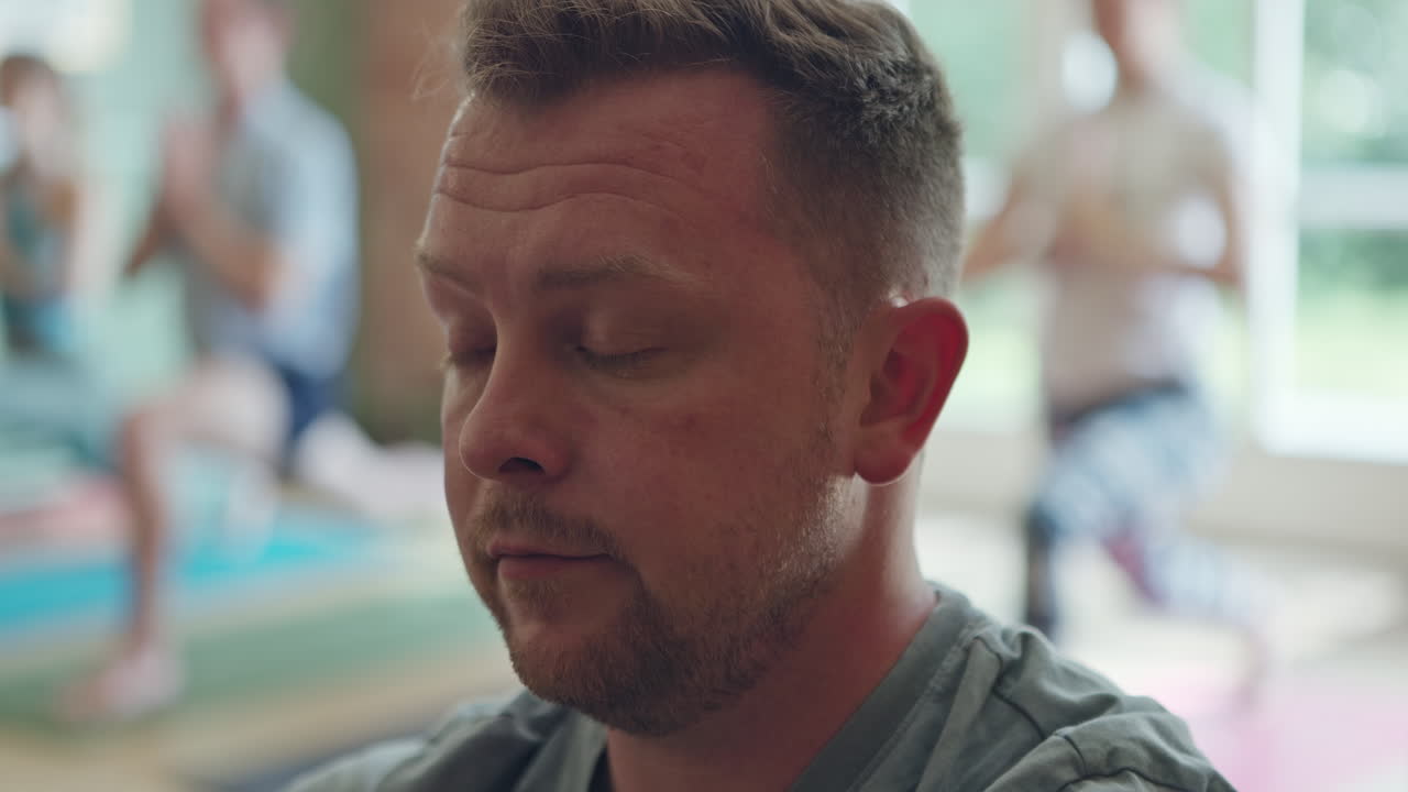 Man practicing yoga with a group indoors