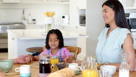 family holding hands and smiling during breakfast at home, enjoying togetherness
