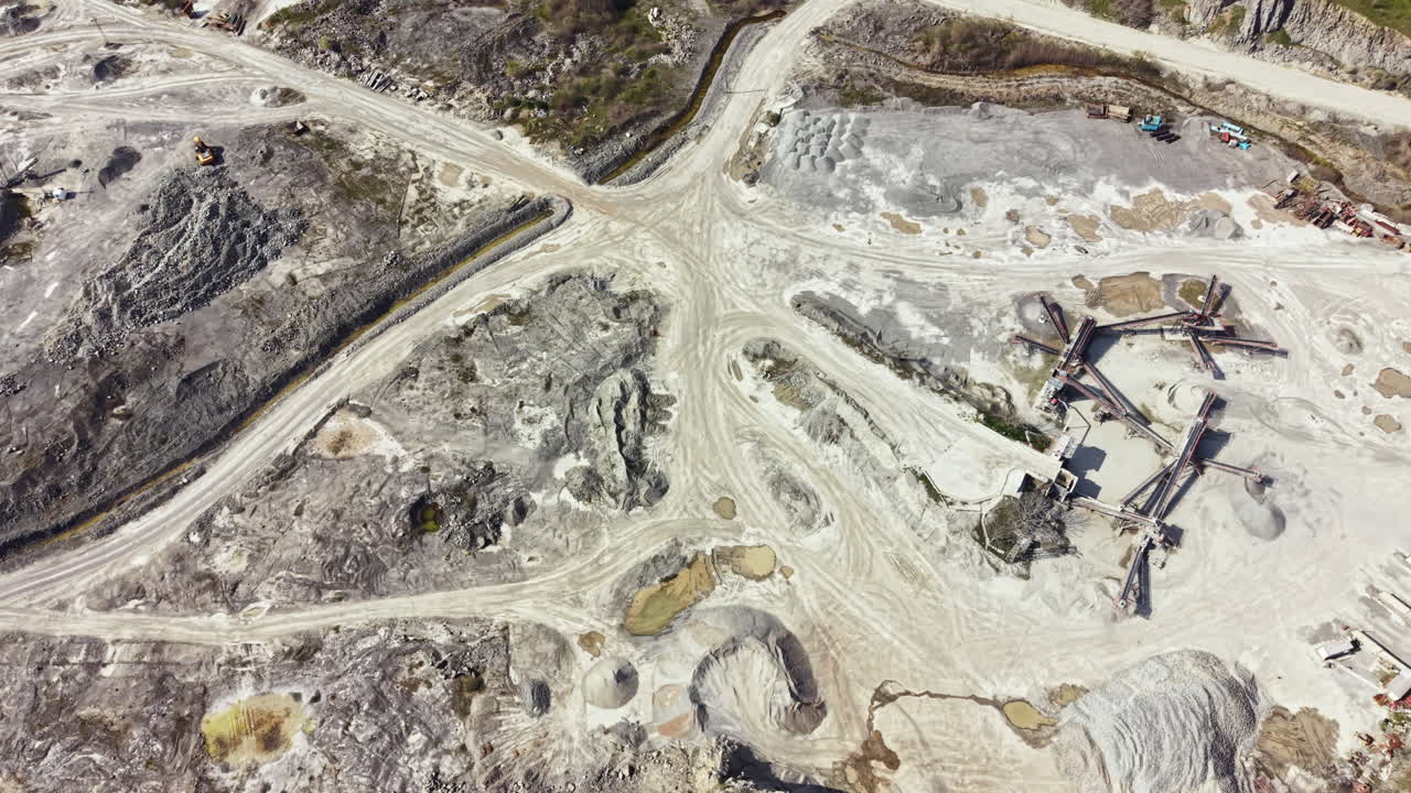 Granite quarry located in an industrial area showing large machinery, stockpiles, and vehicle pathways during daytime hours