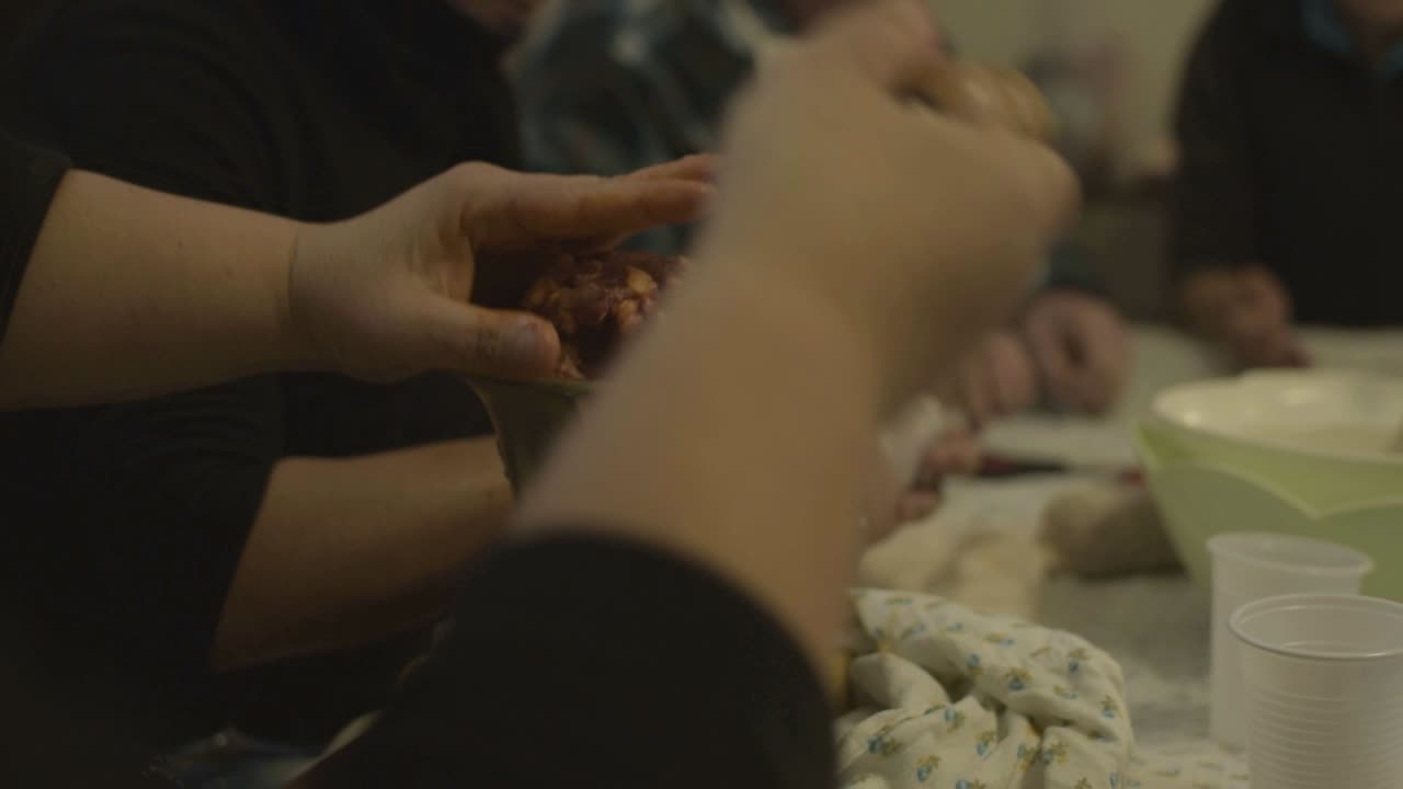 소시지를 위해 고기를 민서로 으깨면서 손잡이를 돌립니다.