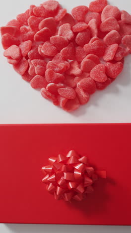 video vertical de vista aérea de dulces rojos en forma de corazón, y regalo envuelto en blanco