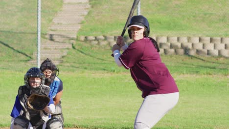 Diverse-group-of-female-baseball-players-playing-on-the-field,-hitter-swinging-for-pitched-ball