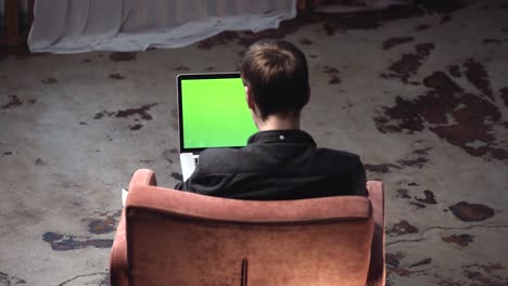 person working on a laptop with a green screen