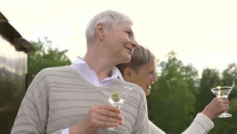 two women talking and having a drink outdoors