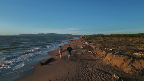 Two-young-persons,-woman-and-man-running-jogging-at-sandy-beach-sea-doing-active-sport-fitness-training-for-marathon-and-staying-fit,-a-healthy-body,-muscles,-endurance