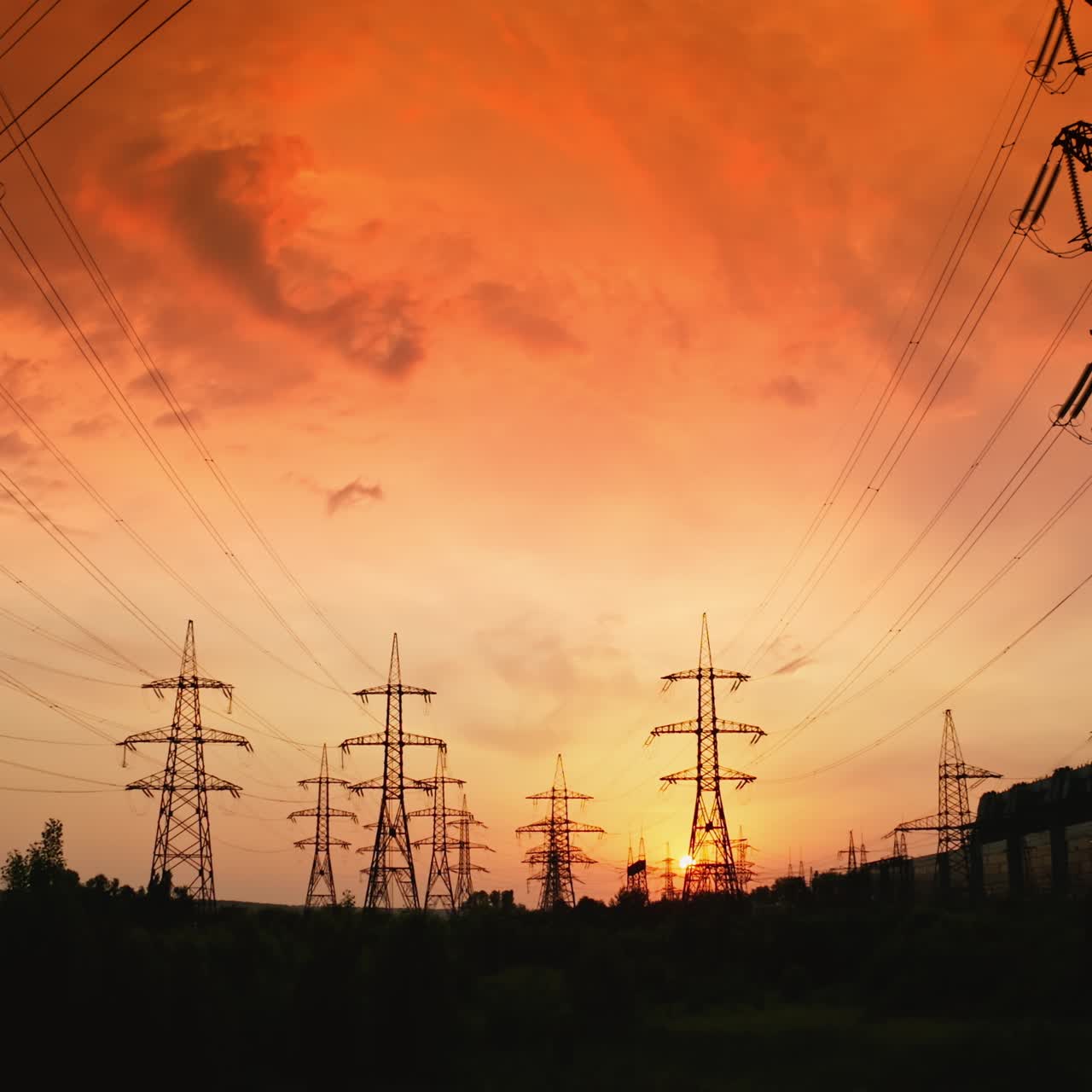 Red sunrise with power lines. Hydro transmission lines and towers making up the electricity grid. Panoramic view of eletric towers at sunset. Motion camera back