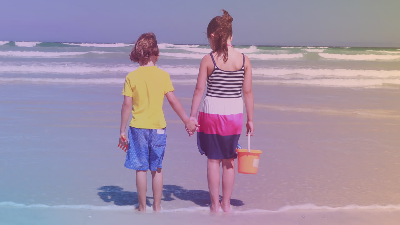 Fratello e sorella caucasici di spalle in piedi sulla spiaggia.