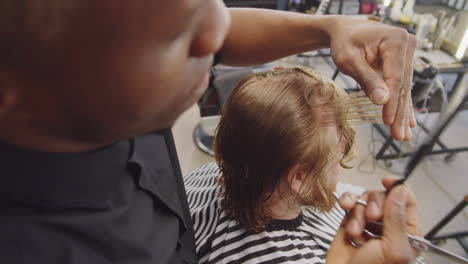 schwarzer friseur schneidet einem kaukasischen kunden die haare