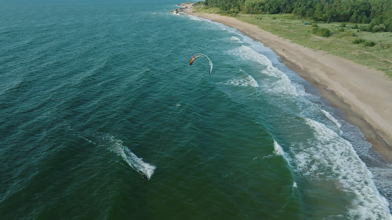 establecimiento de una vista aérea de un grupo de personas dedicadas al kitesurf, día soleado de verano, olas altas, deportes extremos, mar báltico playa de karosta , birdseye drone dolly disparado moviéndose a la derecha