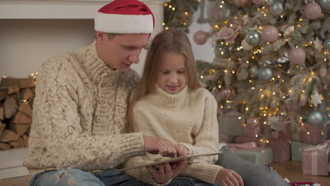 Padre-E-Hija-Usando-Una-Tableta-En-Navidad-Con-Un-Sombrero-De-Santa