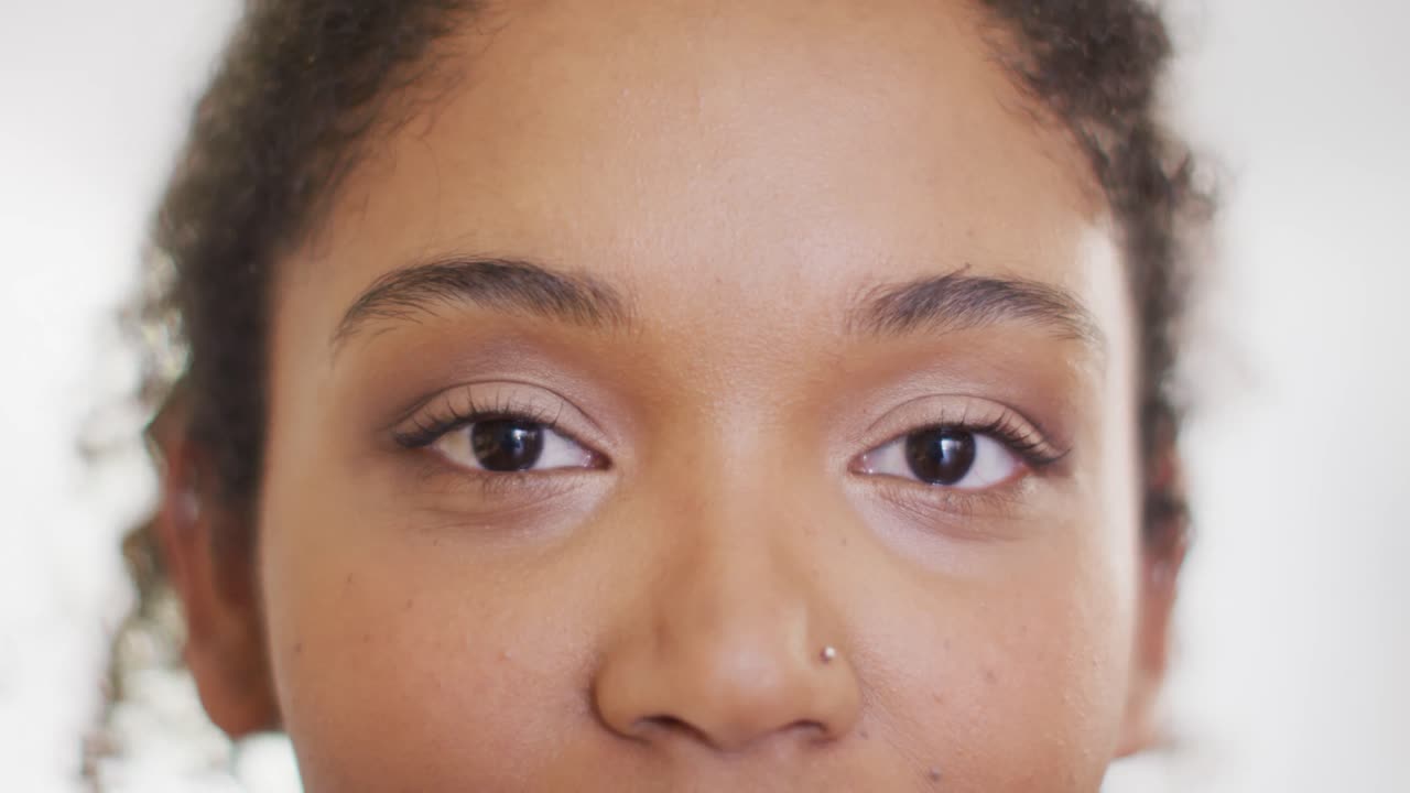 Video close up portrait of the opening and smiling eyes of biracial female doctor in hospital
