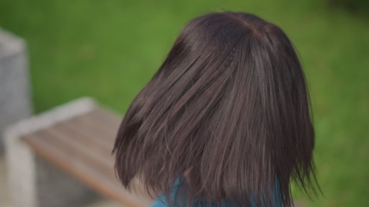 seorang pesepeda wanita melepas helm di luar ruangan, menyesuaikan kacamata hitam dan tersenyum di bangku taman, frame close-up menyertakan tampilan helm dari atas, bagian belakang kepala, profil samping, dan ekspresi santai, atasan teal
