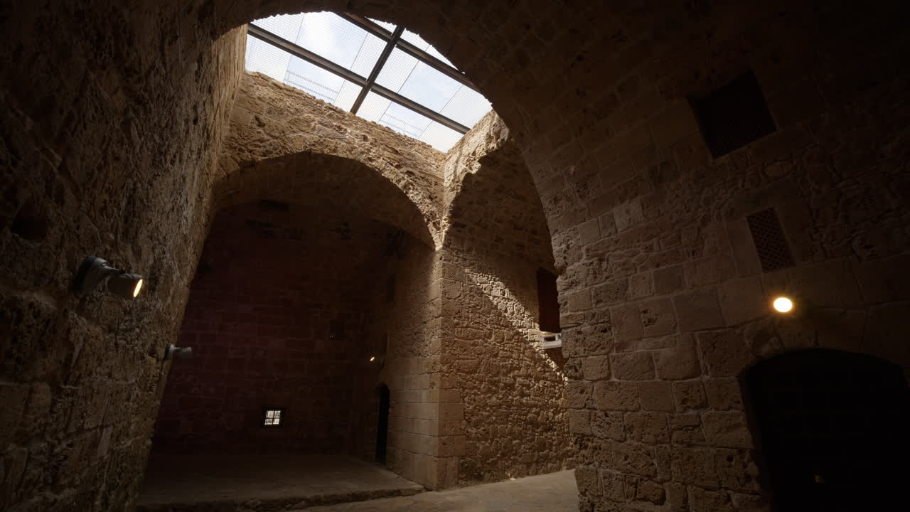 Interior de pedra histórico com arcos abobadados e luz natural entrando por uma abertura no teto. Arquitetura antiga em Pafos refletindo o património cultural.