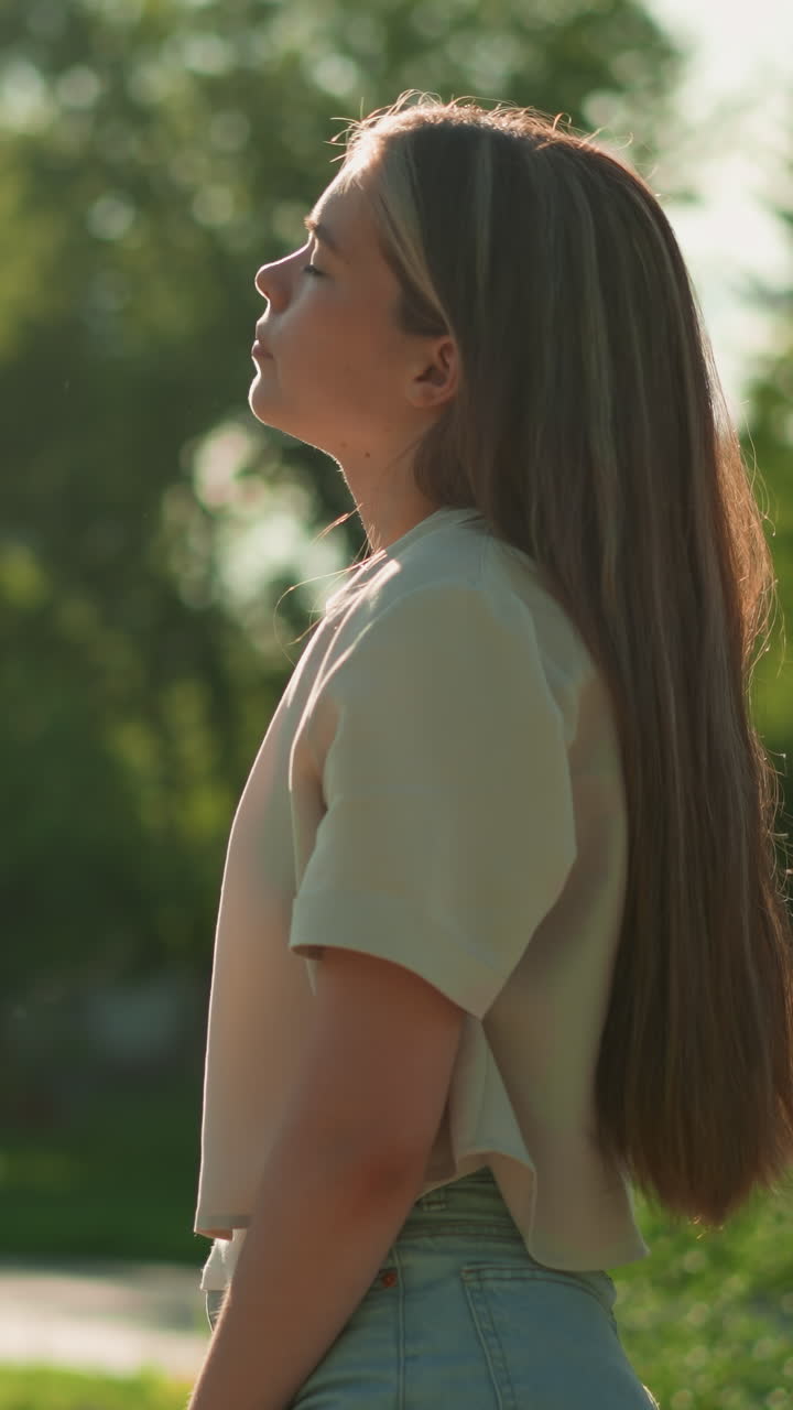 la ciclista se inclina hacia atrás con la cabeza ligeramente inclinada, saboreando la cálida luz del sol mientras su mano descansa en el manillar de la bicicleta, la vegetación y los árboles de enfoque suave