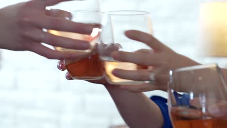 group of women cheers and drink glasses on white wine while sitting at a table with stemless wine glasses