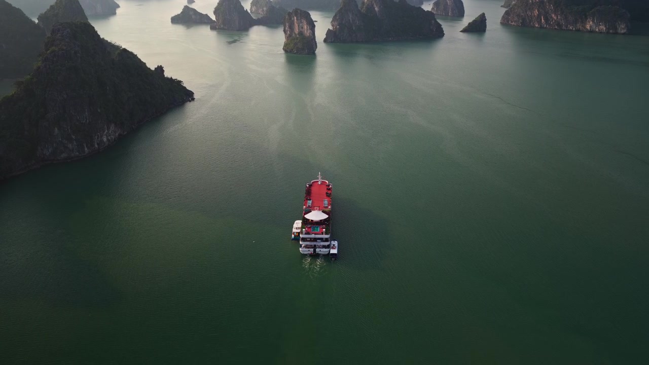 Cảnh quay trên không Vịnh Hạ Long Việt Nam: Du thuyền sang trọng đang lướt trên mặt nước xanh ngọc bích êm ả bên cạnh các khối đá vôi