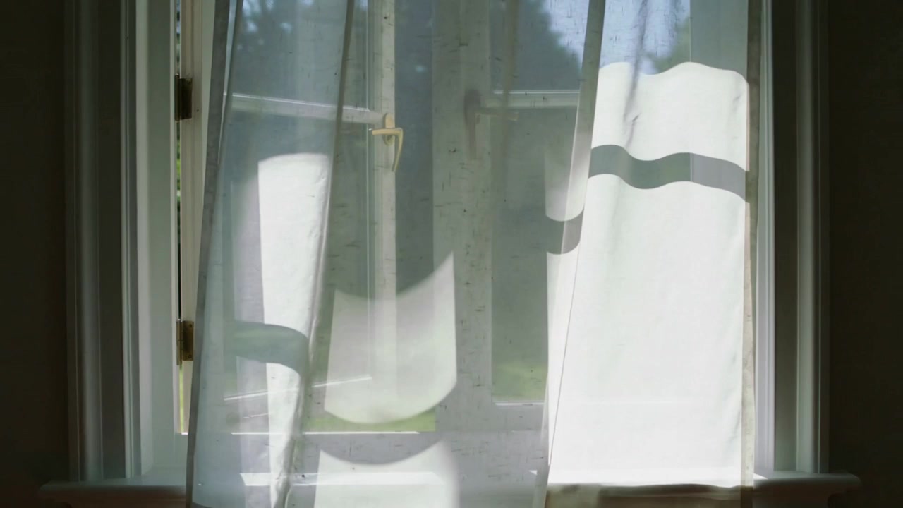 Breeze starting striped sheer curtain drifting across open left sash, sunlight casting wavy shadows